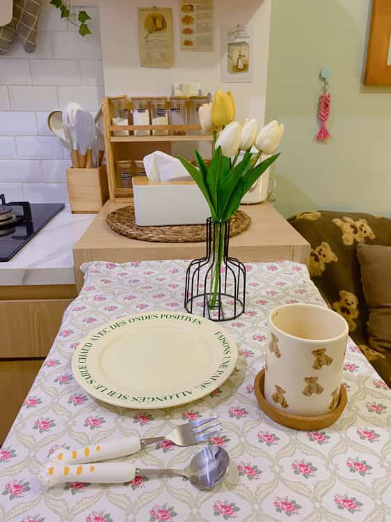 White and wood tone dining room featuring a vase with tulips on the dining table and neat kitchen utensils in a cozy setting