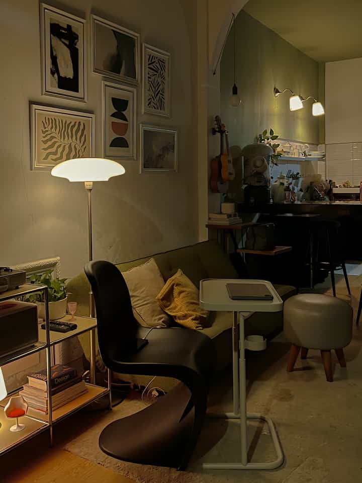 Green-toned Mid-Century Modern open plan living room and kitchen featuring vintage sofa and floor lamp in a cozy setting