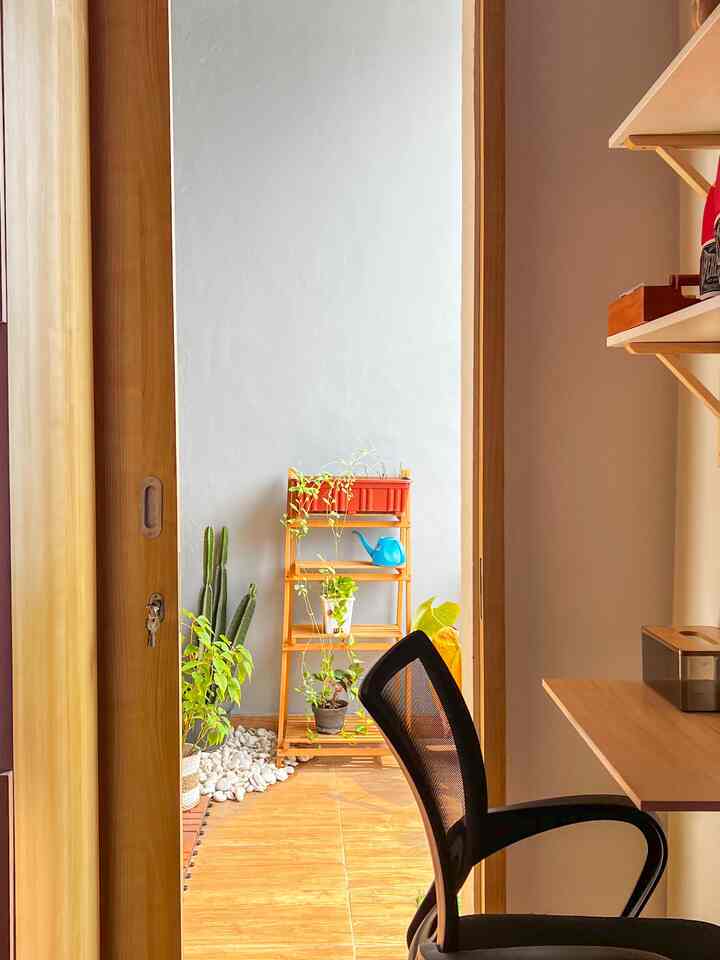 Natural wood tone and white wall small room featuring balcony with plants and a desk setup