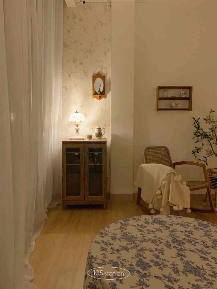 Warm beige and wood tone studio space featuring a vintage table lamp and a floral dining tablecloth creating a cozy atmosphere
