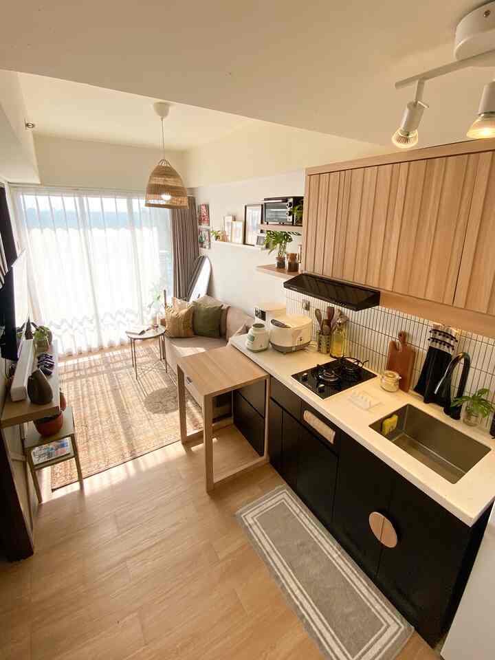 Bright white and wood-tone apartment living room and kitchen featuring bohemian cushions and woven pendant light creating a cozy atmosphere