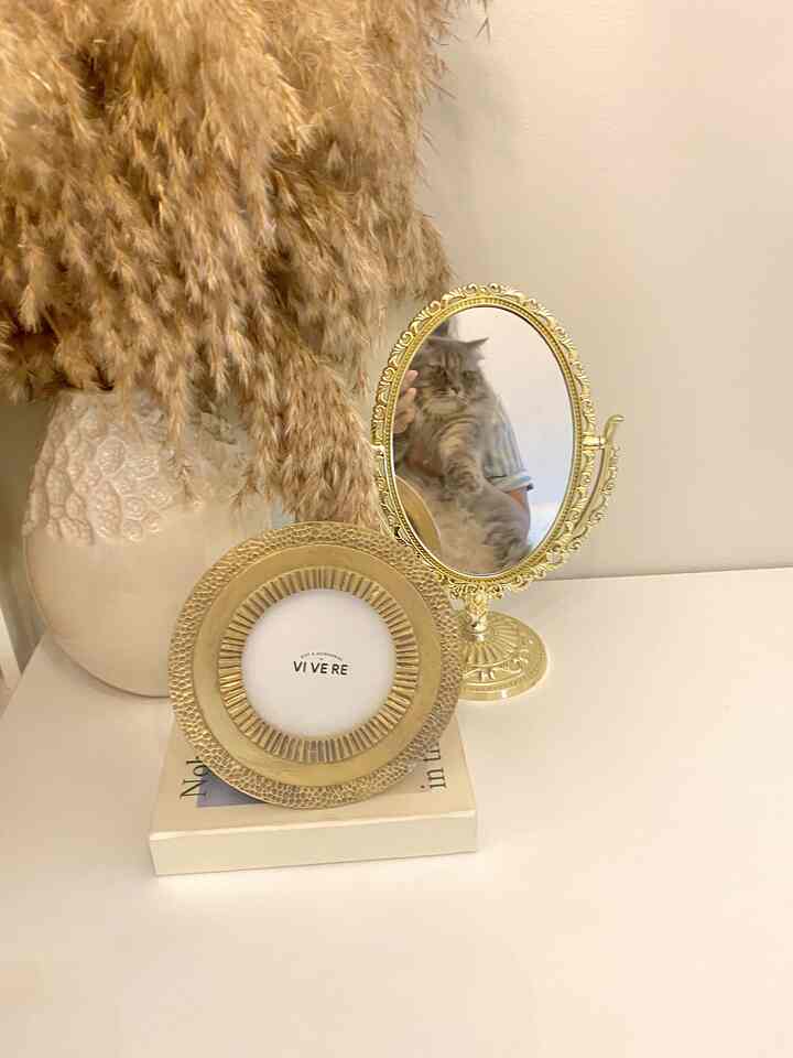 Beige-toned home office desk featuring a beige vase, gold picture frame, and gold oval mirror creating a warm atmosphere