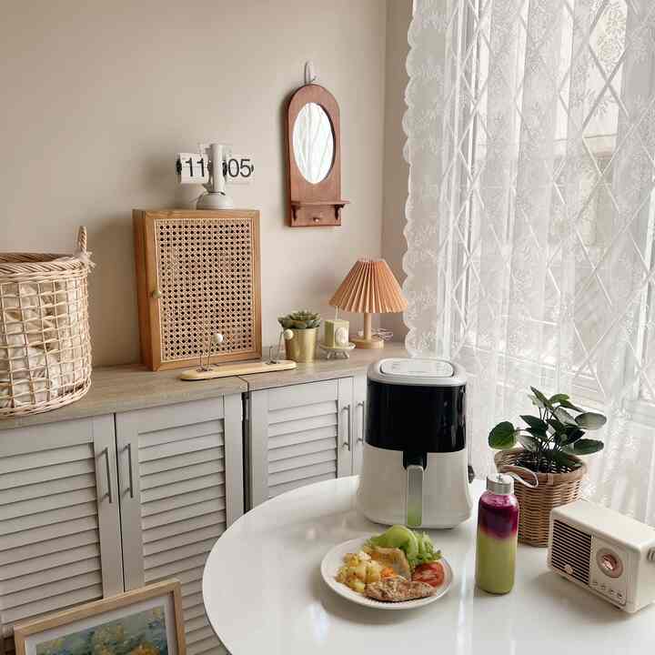 Natural tones and white kitchen space featuring a round dining table with food and beverage, cozy atmosphere with natural decor elements