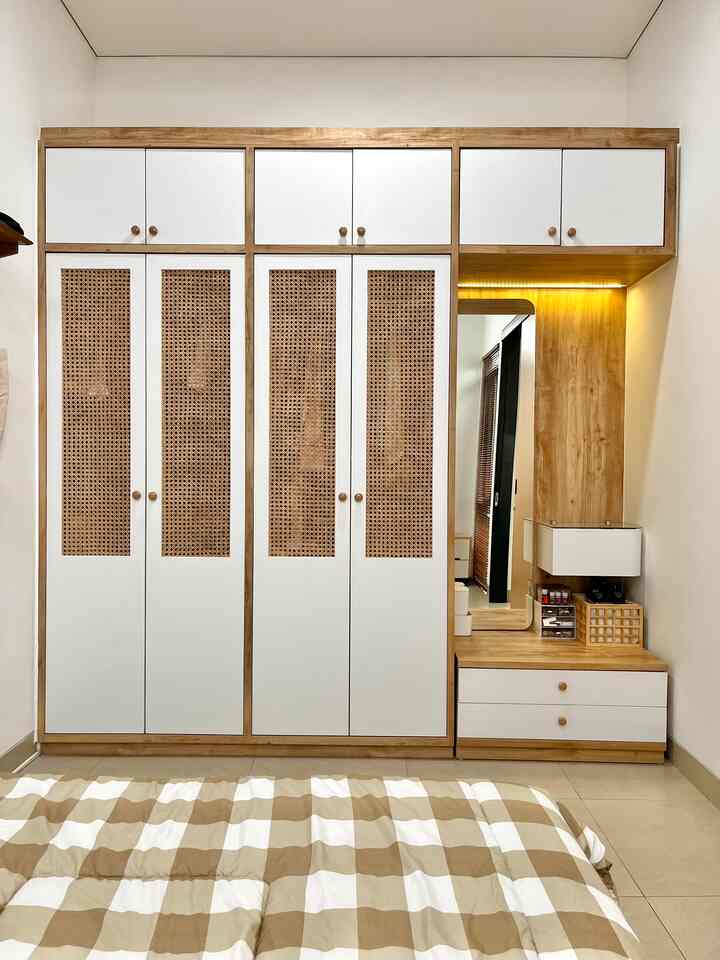 Natural wood tones and white blend in a bedroom featuring a large closet and simple dressing area with a cozy atmosphere