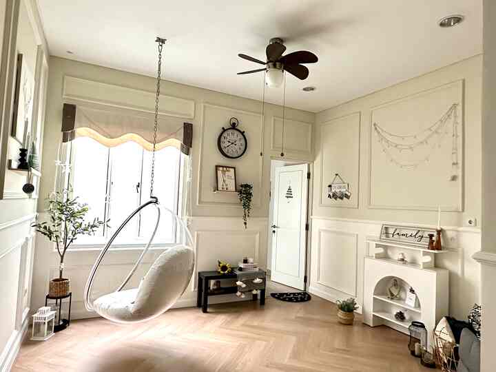 Ivory and wood-toned living room featuring a hanging chair near the window with simple, natural furniture creating a cozy atmosphere