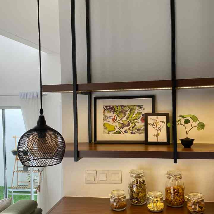 Natural kitchen space with white walls, black shelves, wooden surfaces, framed botanical art, and a small plant