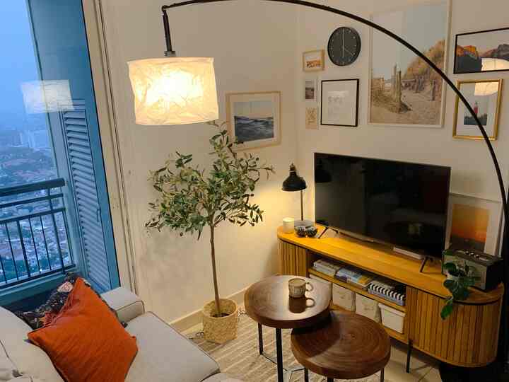 A bright white-walled small living room with wood tone furniture, featuring a home gallery on the wall creating a cozy atmosphere.