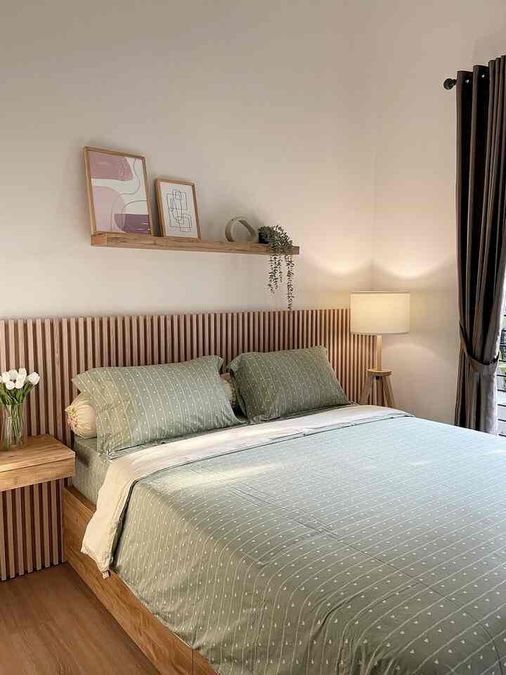 Natural wood tones and soft green bedding in a simple two-person bedroom space
