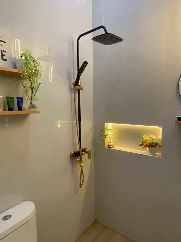 Minimal black and gold bathroom with shower and efficient storage in a compact space