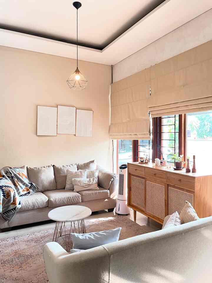 Beige-toned living room featuring natural light window, wooden cabinet, and cream sofas creating a warm atmosphere
