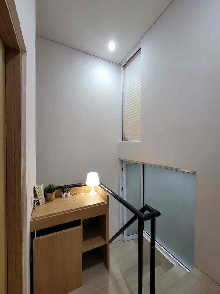 Bright white and natural wood-toned small stair area featuring a minimalist home office setup