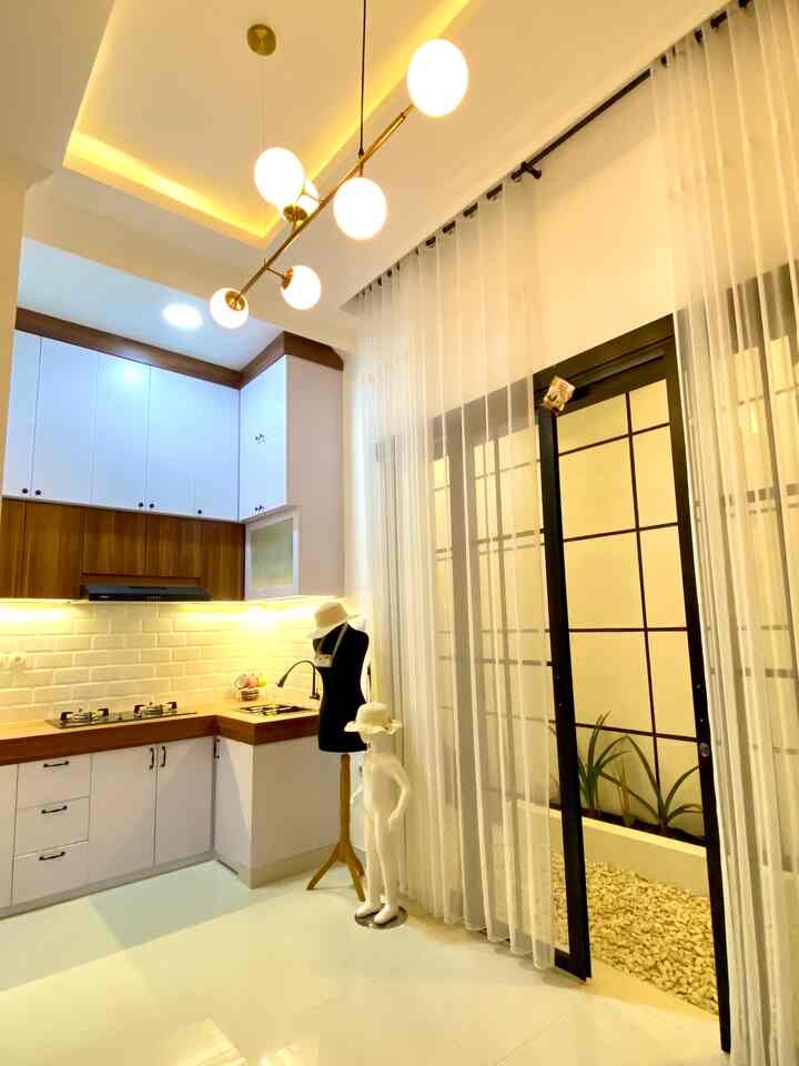White and brown toned kitchen in a long and narrow room, featuring modern pendant lights and curtains.