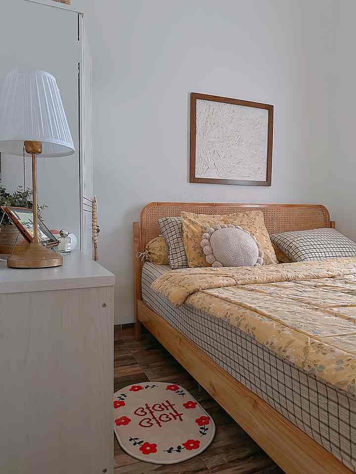 Natural tone small bedroom featuring wood-toned bed with yellow duvet cover in a cozy layout