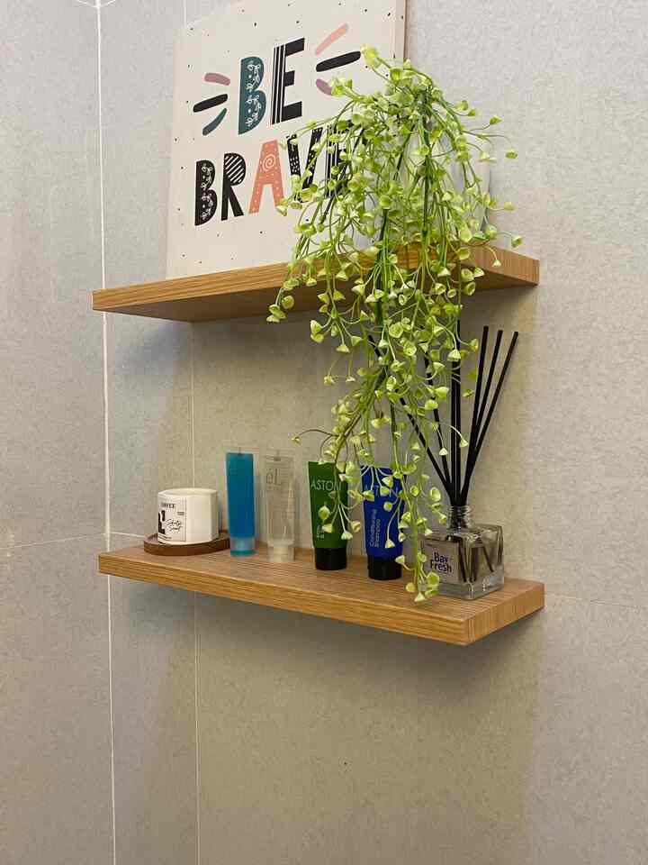 Beige-toned bathroom corner with wood tone shelves and hanging plant, creating a clean and natural vibe