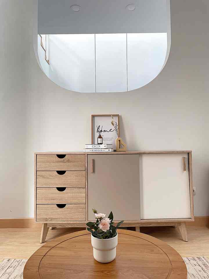 Natural tone living room featuring wooden cabinet and round table with a potted plant, presenting a simple space