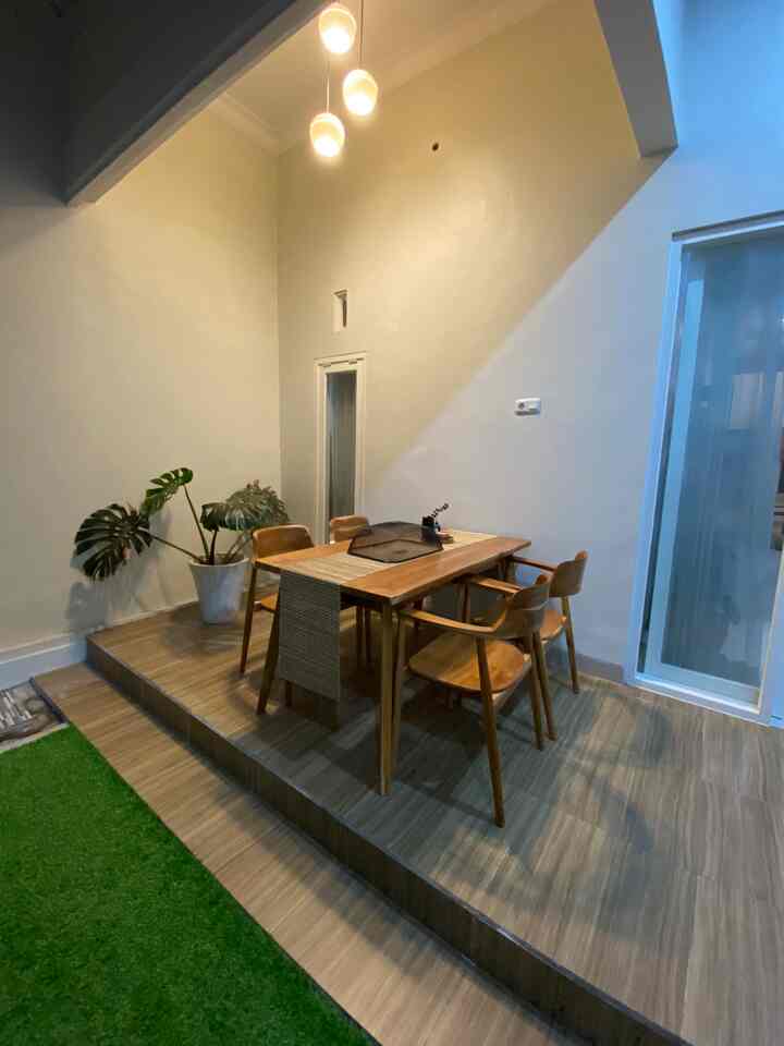 Natural-toned dining room featuring wooden table, chairs, potted plant, and soft pendant lighting creating cozy atmosphere