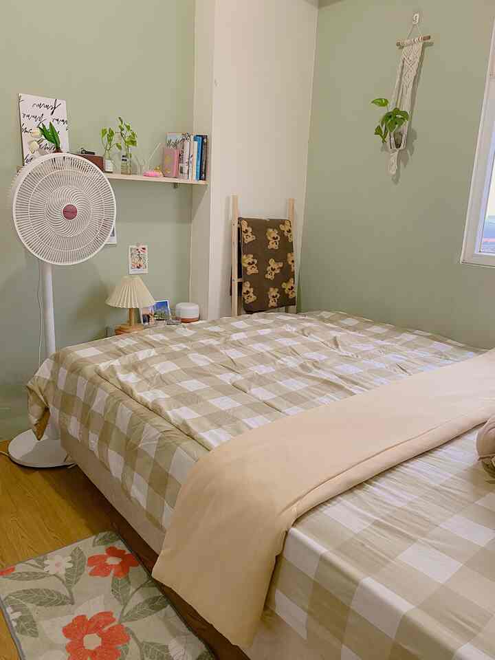 Cozy bedroom with soft green walls and beige-brown gingham check bedding creating a natural modern tone