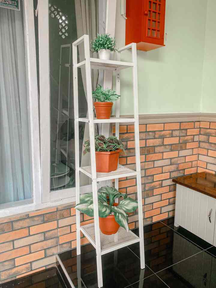 White and brown toned balcony space featuring a white shelf with multiple potted plants in a cozy atmosphere