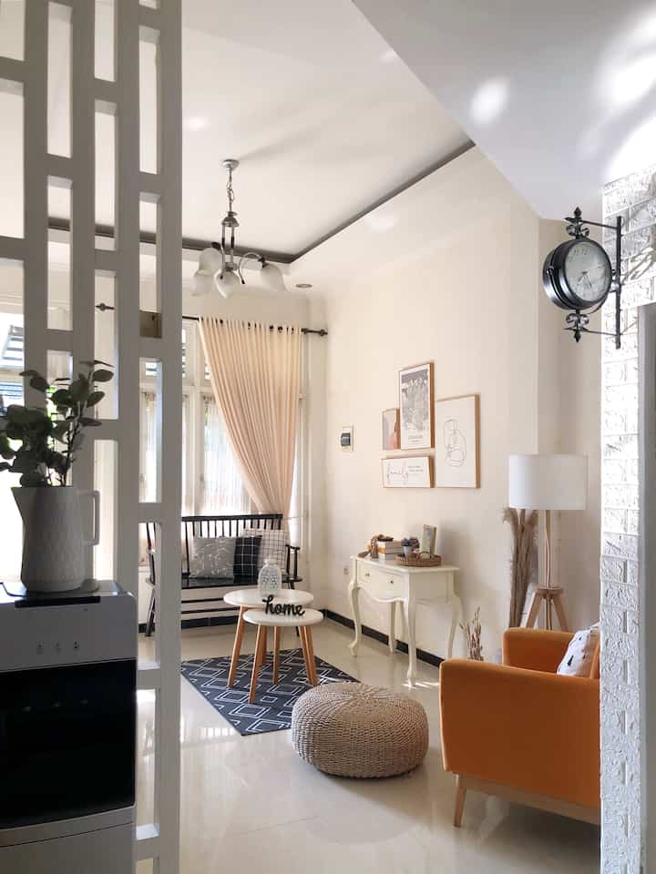Ivory and brown toned living room featuring an orange armchair and black bench sofa in a simple natural space
