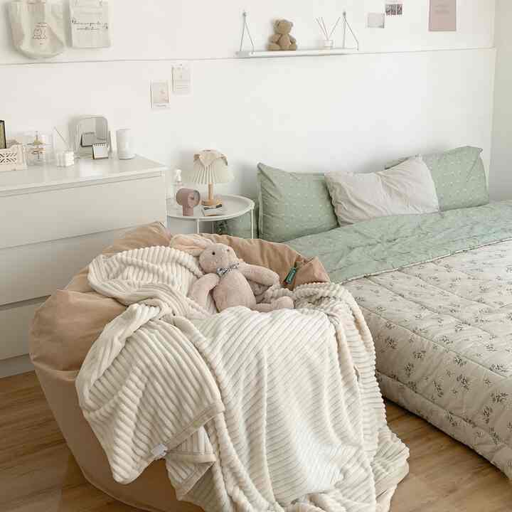 Natural-toned bedroom featuring a beige bean bag with a plush bunny and white blanket, creating a cozy atmosphere