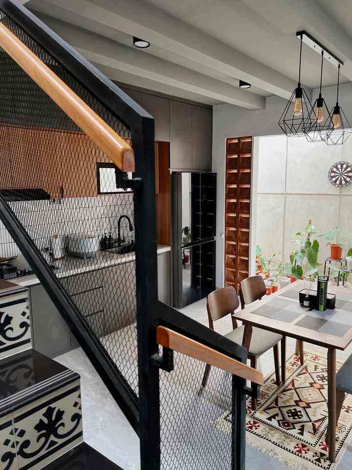 Gray-toned industrial kitchen space featuring wood-tone dining table and chairs blended with natural plant elements