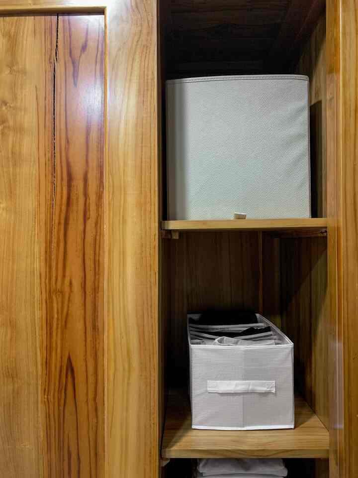 Brown wood-tone wardrobe storage space featuring white storage boxes neatly organized inside shelves with a natural warm atmosphere