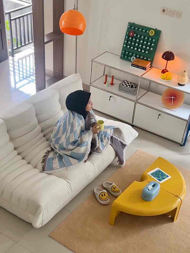 Bright white mid-century modern living room with a white sofa, yellow coffee table, and beige rug creating a cozy ambiance