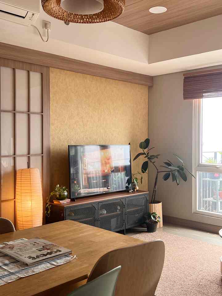 Wood tone and beige living and dining area featuring black TV stand and large window creating a warm atmosphere