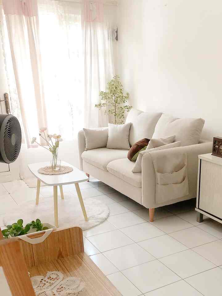 Bright white-toned living room featuring simple natural sofa and round carpet with cozy atmosphere