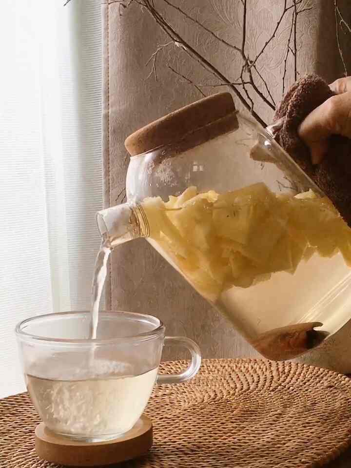 Transparent glass teacup and kettle pouring warm beverage over beige woven mat in cozy home cafe setting