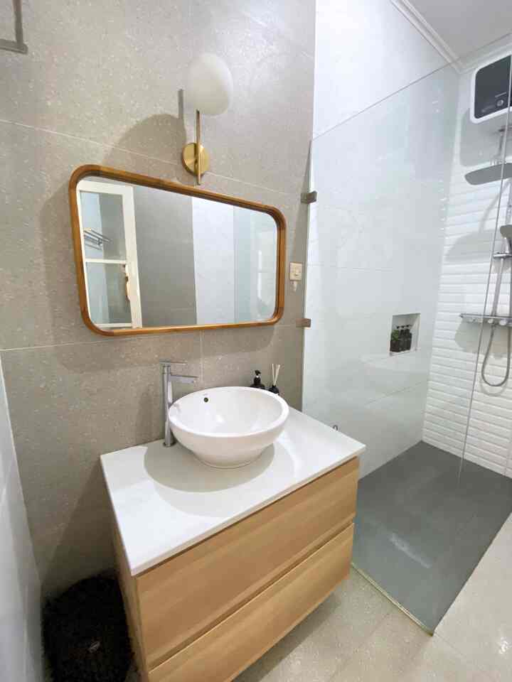 Natural wood tone and white dominant long, narrow compact bathroom featuring vanity with mirror and shower booth in a neat layout