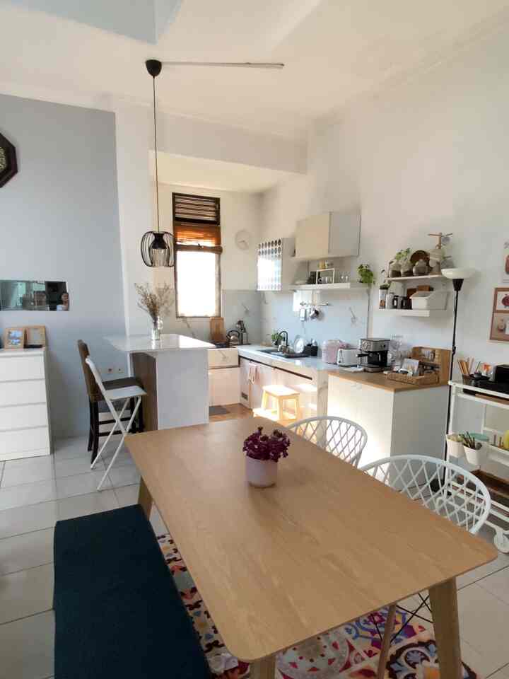 A long and narrow kitchen and dining room space in white and wood tones, featuring a modern dining table and chairs with a cozy atmosphere