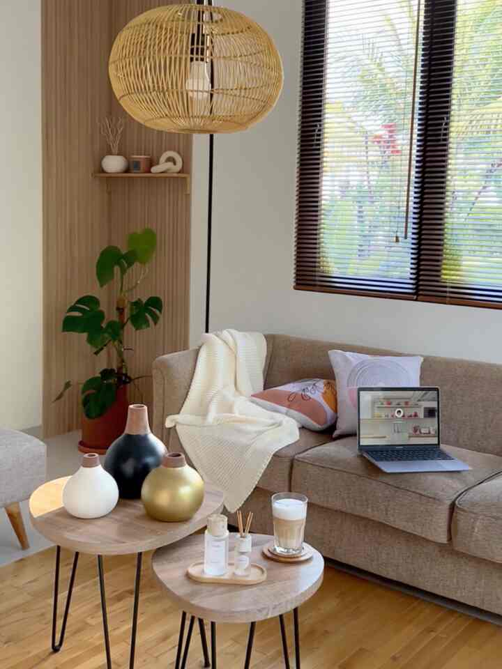 Warm brown and wood tone living room featuring a sofa with a laptop and a floor lamp creating a cozy atmosphere