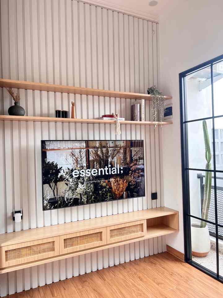 White walls with wood tone floor, shelves, and rattan cabinet create a Japandi style living room space