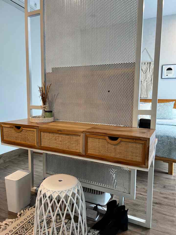Modern bedroom with white and wood tones featuring a console table with drawers and a white stool