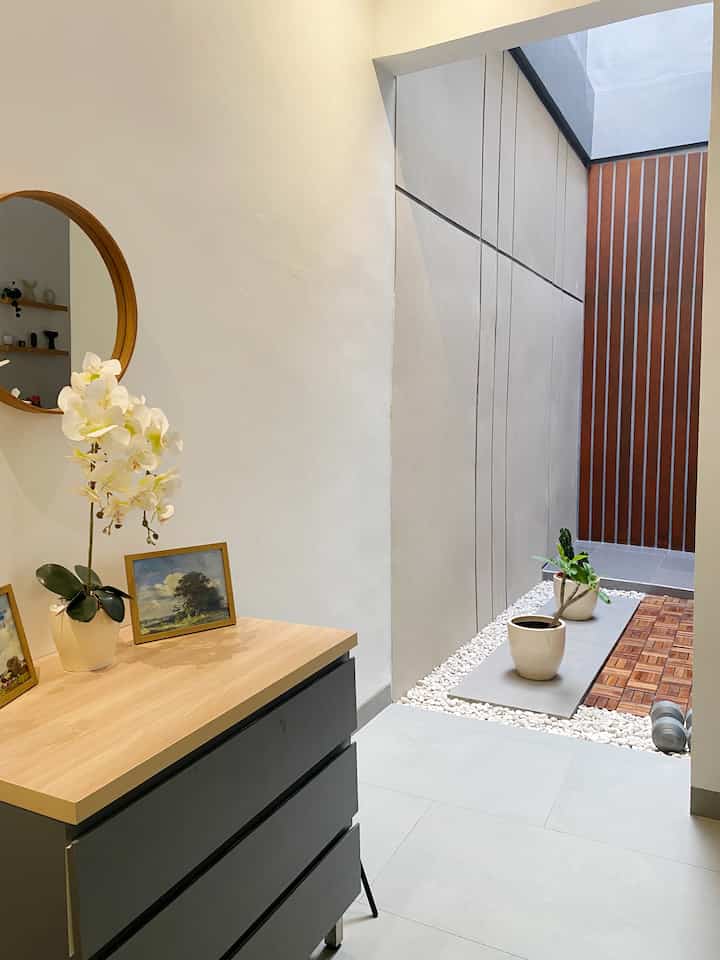 White and wood tone entrance space featuring a dresser with mirror and plants, showcasing a simple and natural minimalist interior