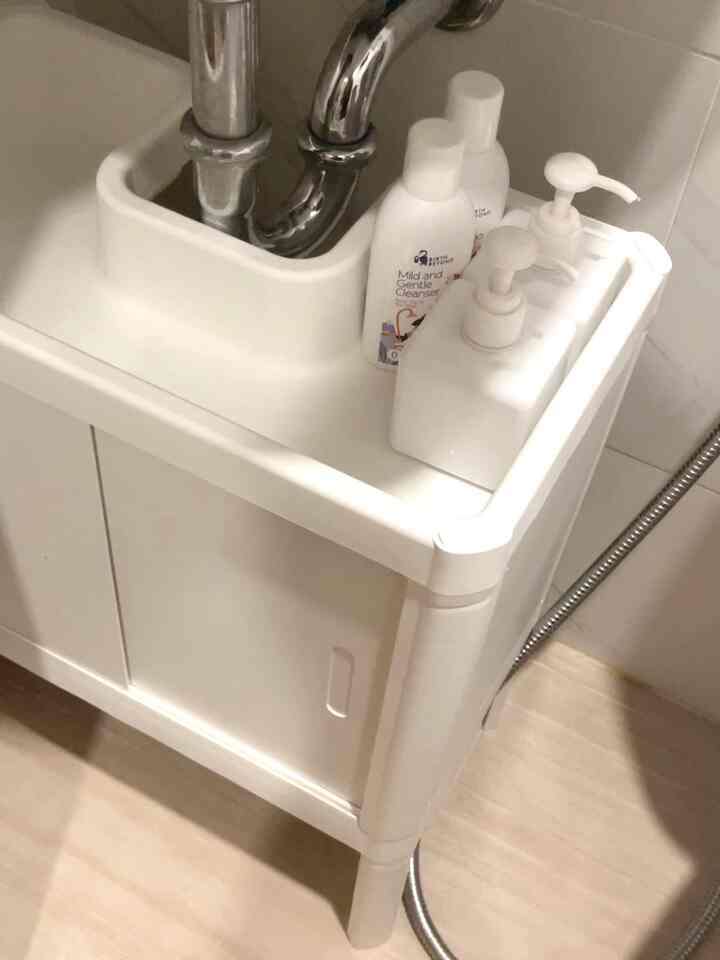 White-toned bathroom space featuring a white sink cabinet with soap dispensers, creating a clean and compact interior