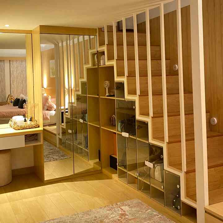 Warm wood tone Japandi bedroom featuring wall sconces and under-stair storage in a cozy natural interior