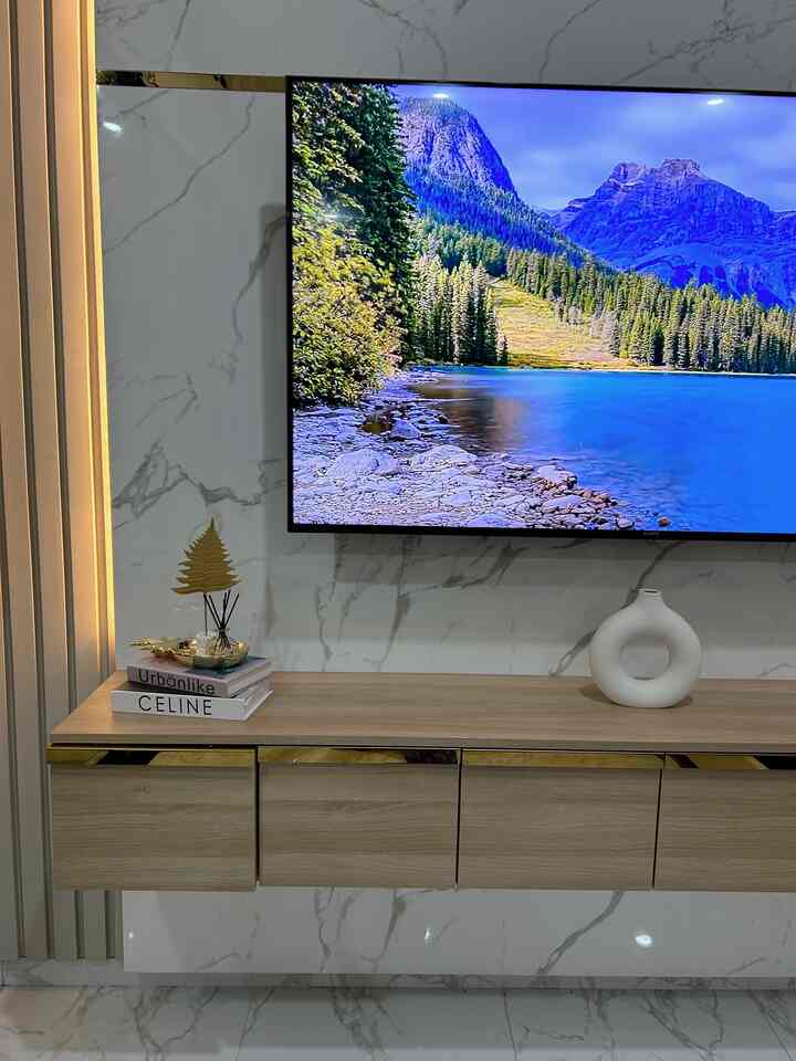 Modern living room featuring white marble wall, gold accents, and a wooden TV stand with decorative elements