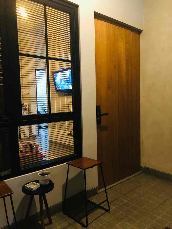Wooden door and blinds at entrance, child and living room visible through window creating a warm indoor atmosphere