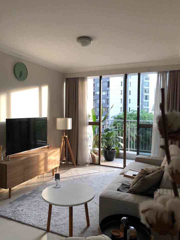 Light gray and wood tone living room featuring sofa and coffee table with balcony view, creating a cozy and natural modern atmosphere