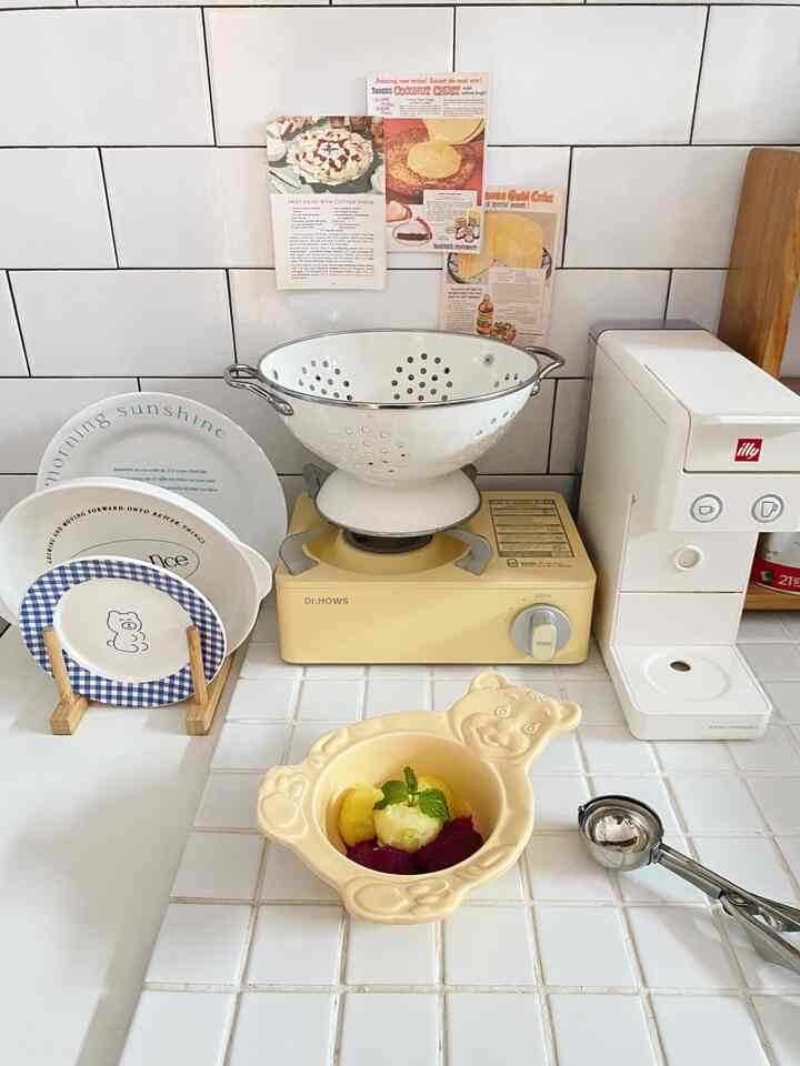 Clean kitchen counter space with yellow gas stove and white tiled wall backsplash