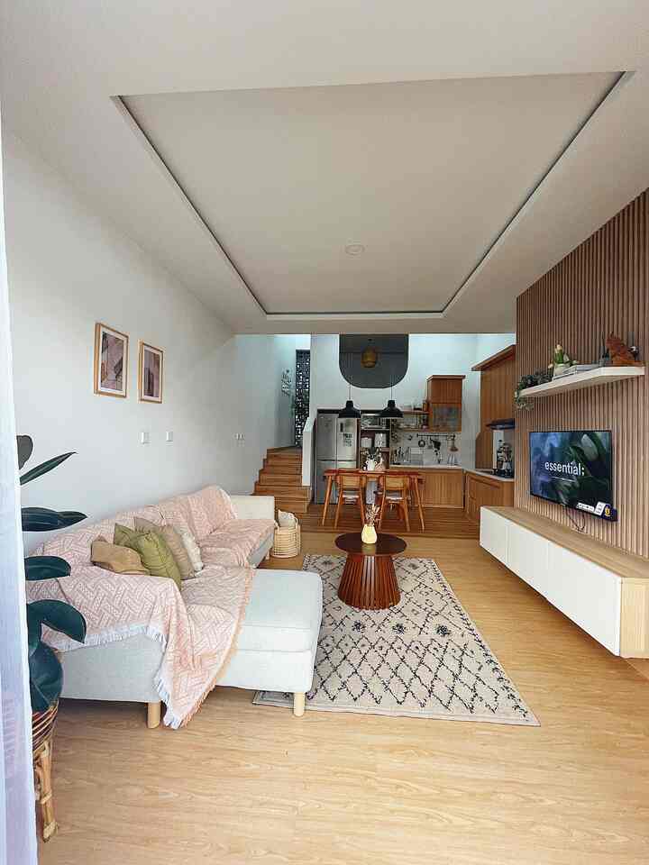 Natural and white toned living room and kitchen featuring wood tone furniture, bohemian rug, and pendant lights with cozy atmosphere