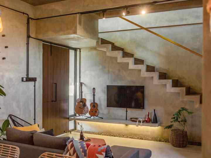 Beige and wood-toned living room featuring modern industrial style with TV and decor utilized under stairs