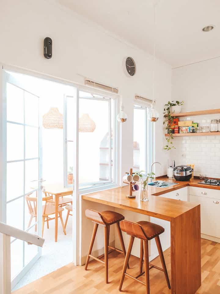 Bright white and wood-toned Japandi kitchen featuring bar stools and dining chairs, creating a cozy and aesthetic atmosphere