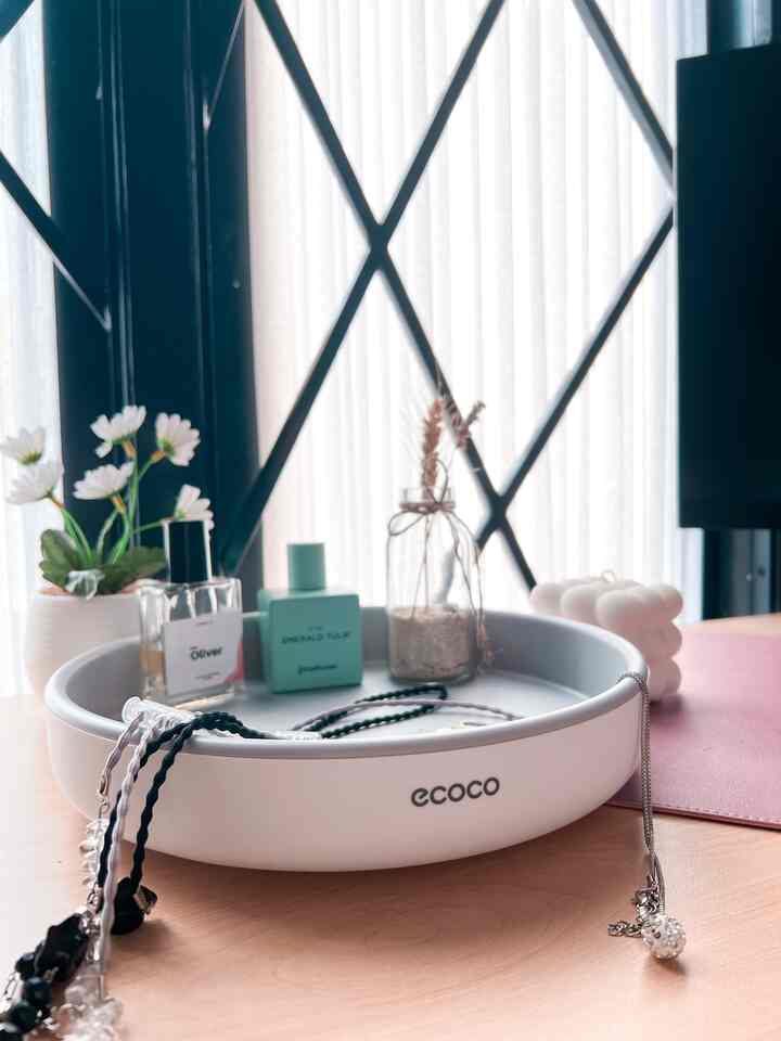 White and wood tone table featuring a central Ecoco 360° rotating storage box, perfume bottles, and decorative elements in a minimal and tidy space