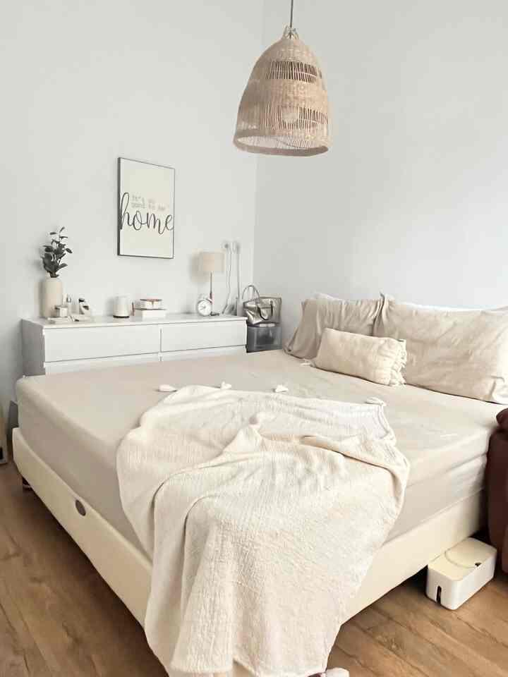 Bedroom with beige and wood tones, featuring a large bed and dresser creating a natural and cozy atmosphere