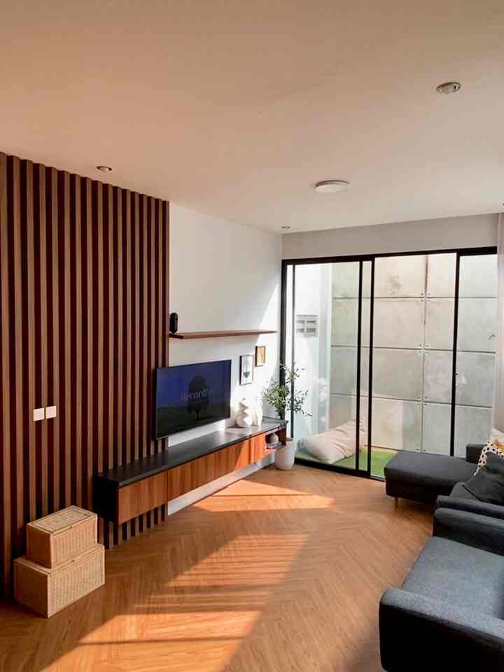 Wood tone and gray living room featuring gray sectional sofa, wood slat wall, floor-to-ceiling sliding glass door creating a cozy minimalist space