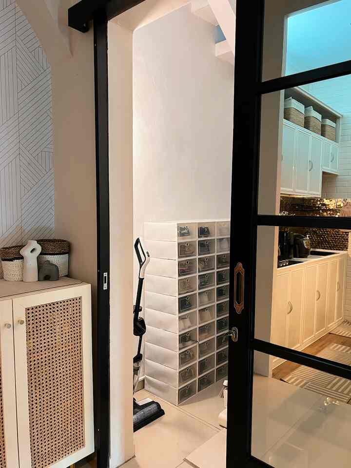 White and black toned storage area with shoe drawers and stairs next to a kitchen space