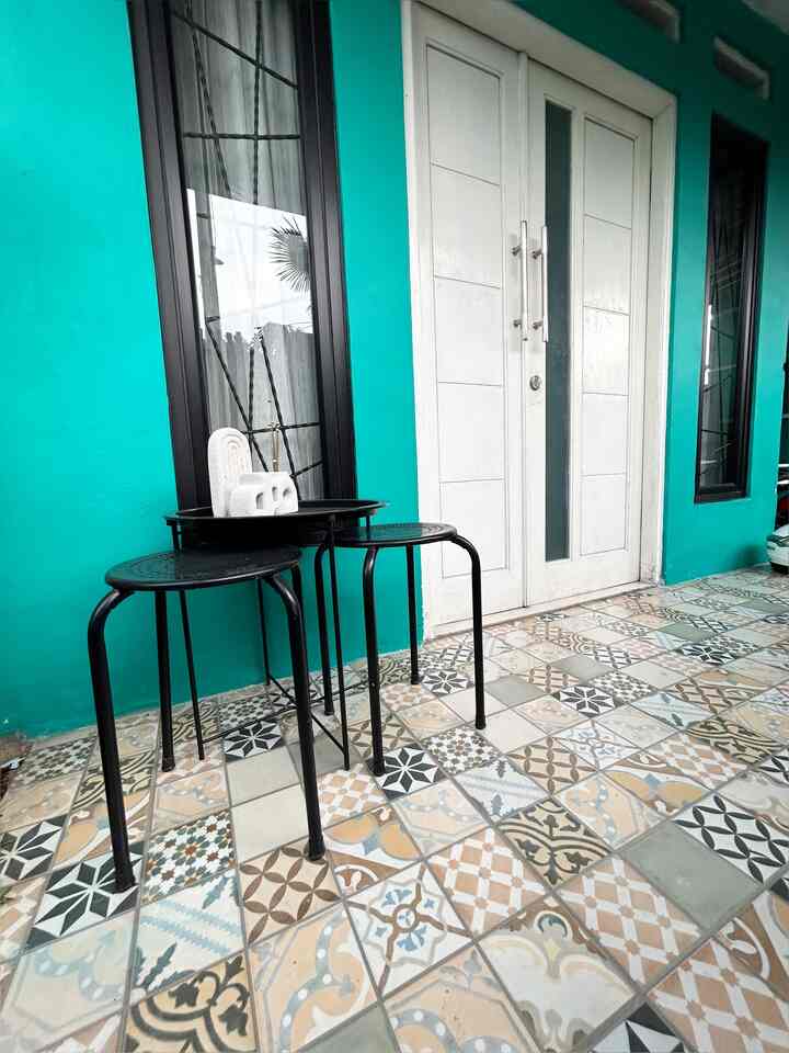 Modern balcony space with turquoise walls, white door, patterned tile flooring, and black corner tables